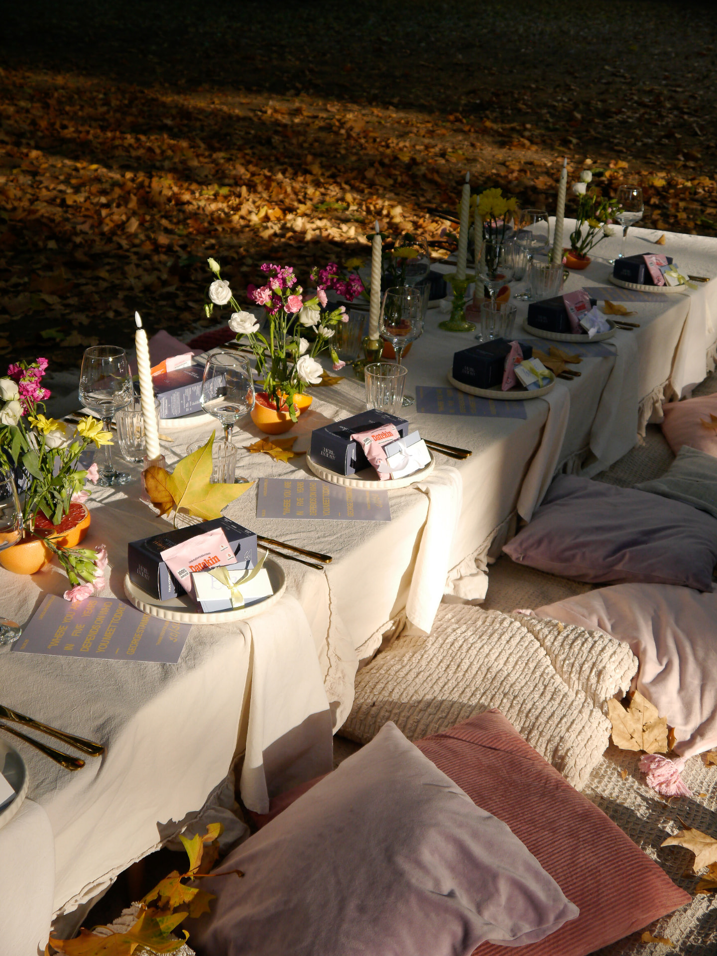 An outdoor her.arca table styled with candles, flowers and cushions